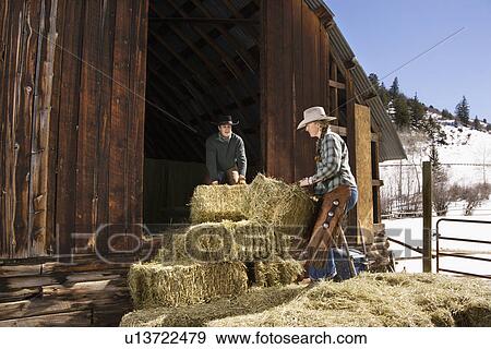 Stock Photo - Attractive Couple Moving Hay Bales. Fotosearch