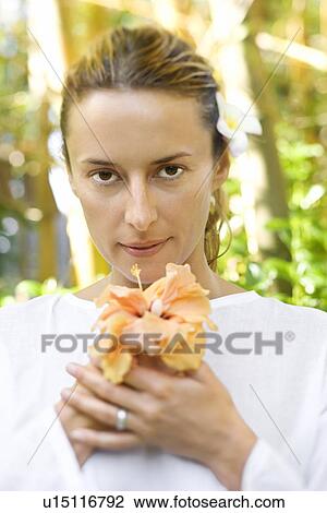 Stock Image - Attractive Woman Holding Flower. Fotosearch