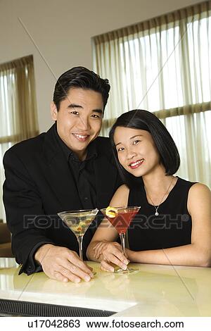 Stock Image - Attractive Young Couple With Cocktails Smiling. Fotosearch