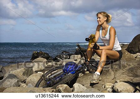 Attractive Young Woman Sitting With Bicycle on Rocky Beach View Large Photo Image Picture - Attractive Young Woman Sitting With Bicycle on Rocky Beach. Fotosearch