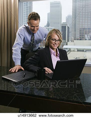 Stock Image - Business people looking at laptop computer. Fotosearch