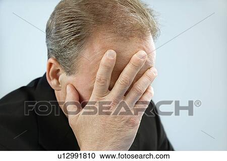 Stock Image - Businessman covering face. Fotosearch