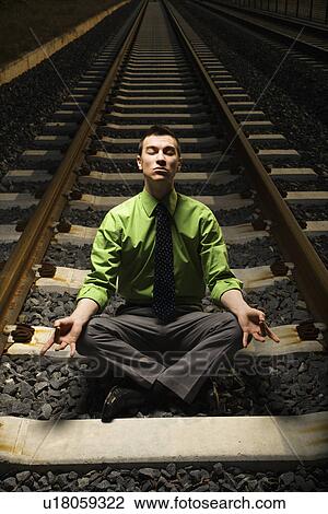 Businessman Meditating on Railroad Tracks. View Large Photo Image Stock Image - Businessman Meditating on Railroad Tracks.. Fotosearch