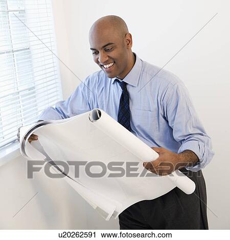 Stock Image - Businessman reading blueprint.. Fotosearch