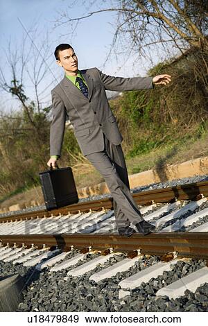 Stock Photo - Businessman Walking on Railroad Tracks. Fotosearch