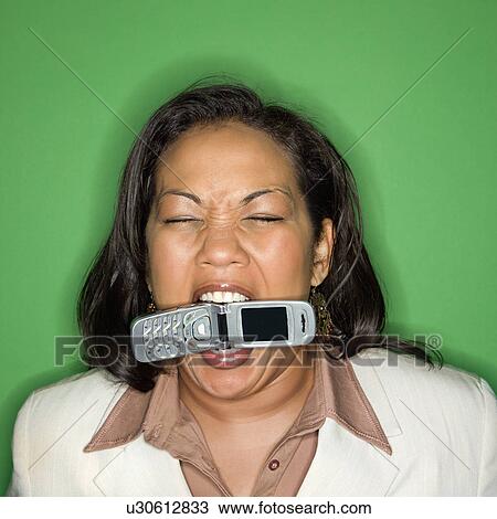 Stock Image - Businesswoman biting cellphone. Fotosearch