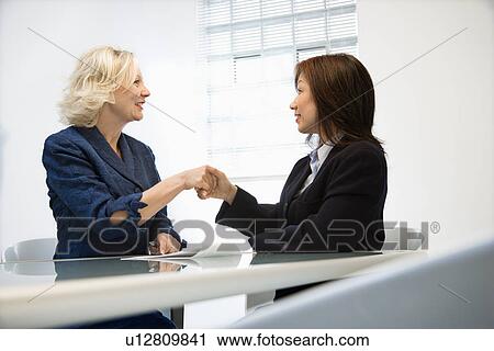 Stock Image - Businesswomen shaking hands. Fotosearch