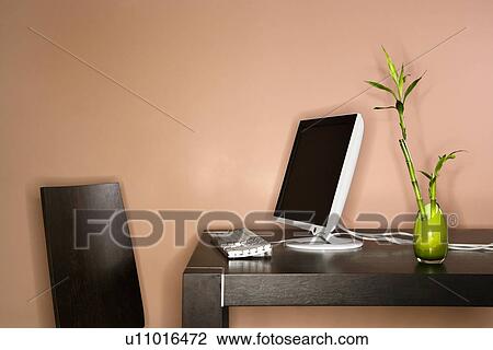 Stock Image - Computer on Table with Bamboo Plant. Fotosearch