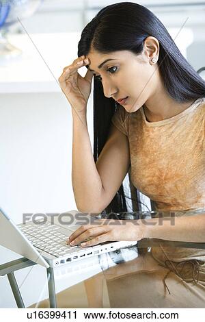Stock Image - Concerned Young Woman Using Laptop. Fotosearch