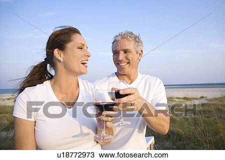 Stock Image - Couple Drinking Wine on Beach. Fotosearch