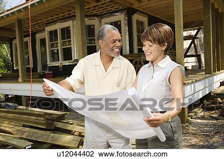 Stock Image - Couple Holding Building Plans. Fotosearch