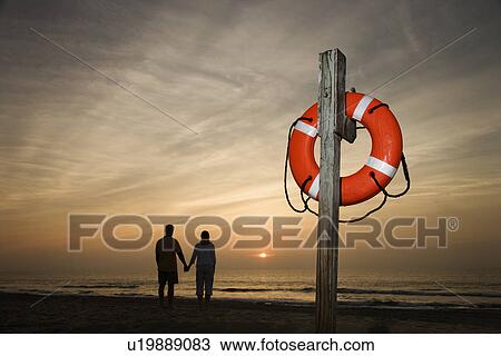 Couple holding hands on beach View Large Photo Image Stock Image - Couple holding hands on beach. Fotosearch