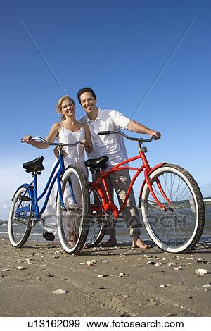 Stock Photo - Couple with Bikes at the Beach. Fotosearch