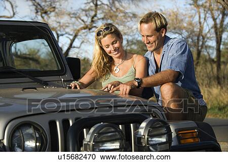 Stock Image - Couple With Map on Car Hood. Fotosearch