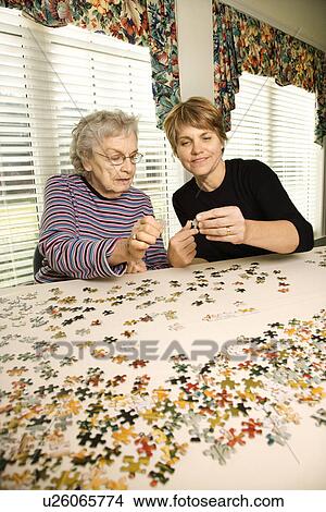 Picture - Elderly Woman and Younger Woman doing a puzzle together. Fotosearch