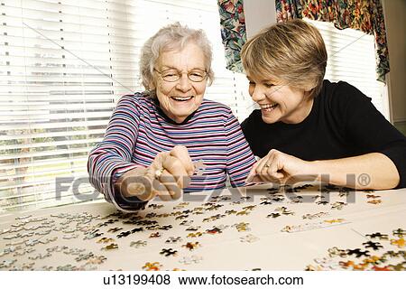 Stock Photo - Elderly Woman and Younger Woman Doing a Puzzle. Fotosearch