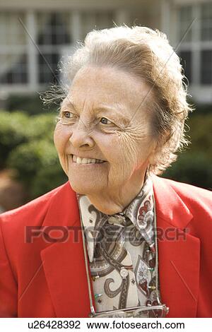 Stock Image - Elderly Woman in Red Coat Outdoors Smiling. Fotosearch