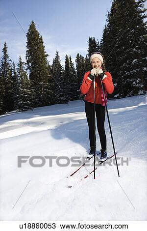 Stock Image - Female Snow Skier Leaning on Poles and Smiling. Fotosearch