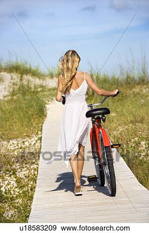 Stock Photo - Girl Walking Bike on Boardwalk. Fotosearch