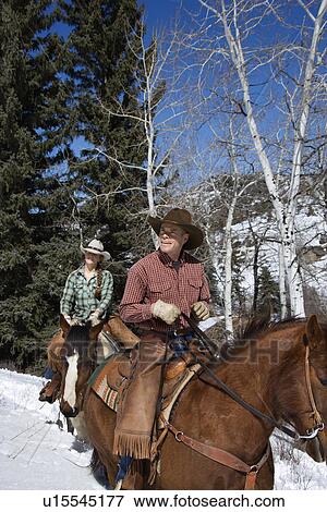 Stock Photo - Man and Woman Riding Horses in the Snow. Fotosearch