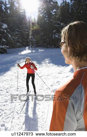 Stock Image - Man and Woman Snow Skiing. Fotosearch