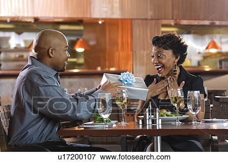 Man Giving Gift to Woman at Restaurant View Large Photo Image Stock Photo - Man Giving Gift to Woman at Restaurant. Fotosearch