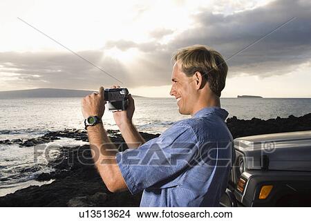Picture - Man Using Video Camera at the Beach. Fotosearch