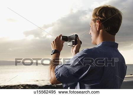 Stock Photography - Man Using Video Camera at the Beach. Fotosearch
