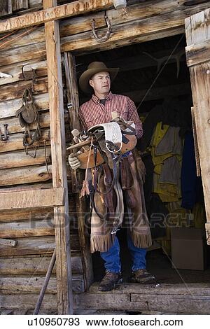 Man Wearing Cowboy Hat Holding a Saddle View Large Photo Image Stock Image - Man Wearing Cowboy Hat Holding a Saddle. Fotosearch
