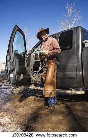 Stock Photo - Man Wearing Cowboy Hat With Lariat and Truck. Fotosearch