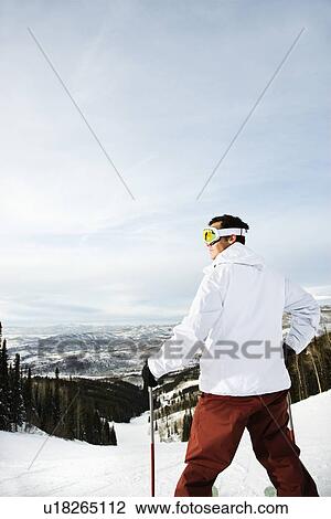 Stock Image - Skier on Mountain Overlooking Valley. Fotosearch