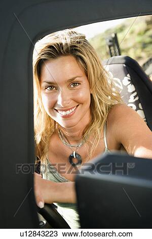 Stock Image - Smiling Woman Sitting in Car. Fotosearch