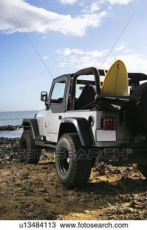 Stock Image - SUV and Surfboard at the Beach. Fotosearch