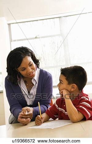 Stock Image - Teacher Helping Boy With Schoolwork . Fotosearch