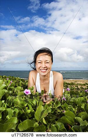 Stock Photo - Woman Lying in Plants Near Beach. Fotosearch
