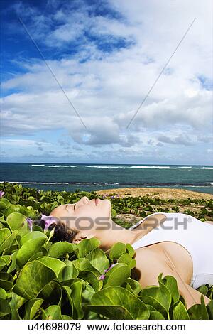 Stock Photo - Woman Lying in Plants Near Beach. Fotosearch