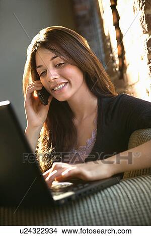Picture - Woman on phone using computer. Fotosearch