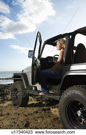 Stock Image - Woman Sitting in an SUV at the Beach. Fotosearch