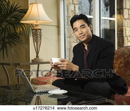 Young Businessman at Laptop Holding a Coffee Cup View Large Photo Image Picture - Young Businessman at Laptop Holding a Coffee Cup. Fotosearch