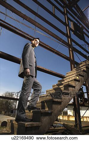Stock Image - Young Businessman Walking Up Stairs. Fotosearch