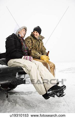 Stock Image - Young Couple Sitting on Truck Tailgate. Fotosearch
