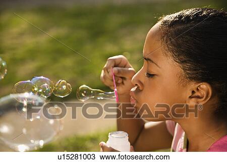 Stock Image - Young Girl Blowing Bubbles. Fotosearch