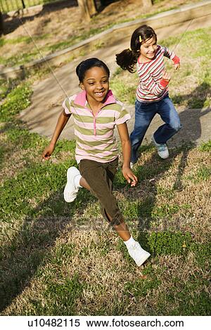 Stock Photography - Young Girls Running on Grass. Fotosearch