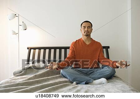 Stock Photo - Young Man Meditating in Bedroom. Fotosearch