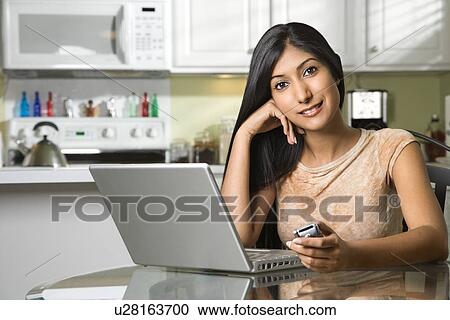 Stock Image - Young Smiling Woman With Laptop and Cellphone. Fotosearch