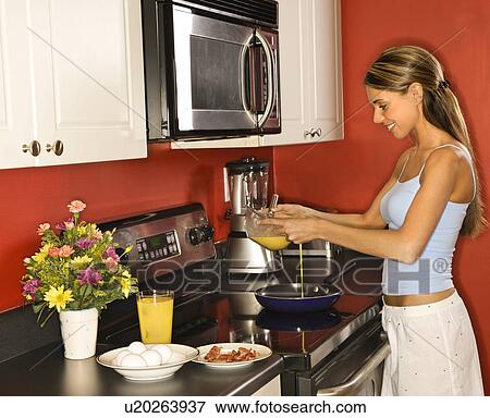 Stock Photo - Young Woman in Kitchen Cooking Breakfast. Fotosearch