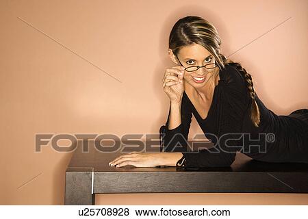 Stock Photo - Young Woman Looking Over Her Glasses Smiling. Fotosearch