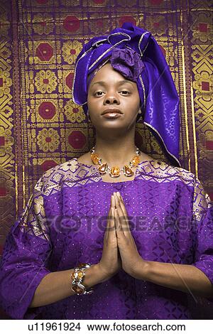 Picture - Young Woman Praying and Wearing Traditional African Dress. Fotosearch
