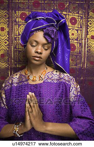 Stock Photo - Young Woman Praying and Wearing Traditional African Dress. Fotosearch