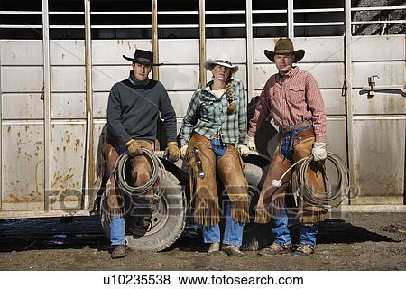 Stock Photo - Young Woman Standing Next to Two Men with Lariats. Fotosearch